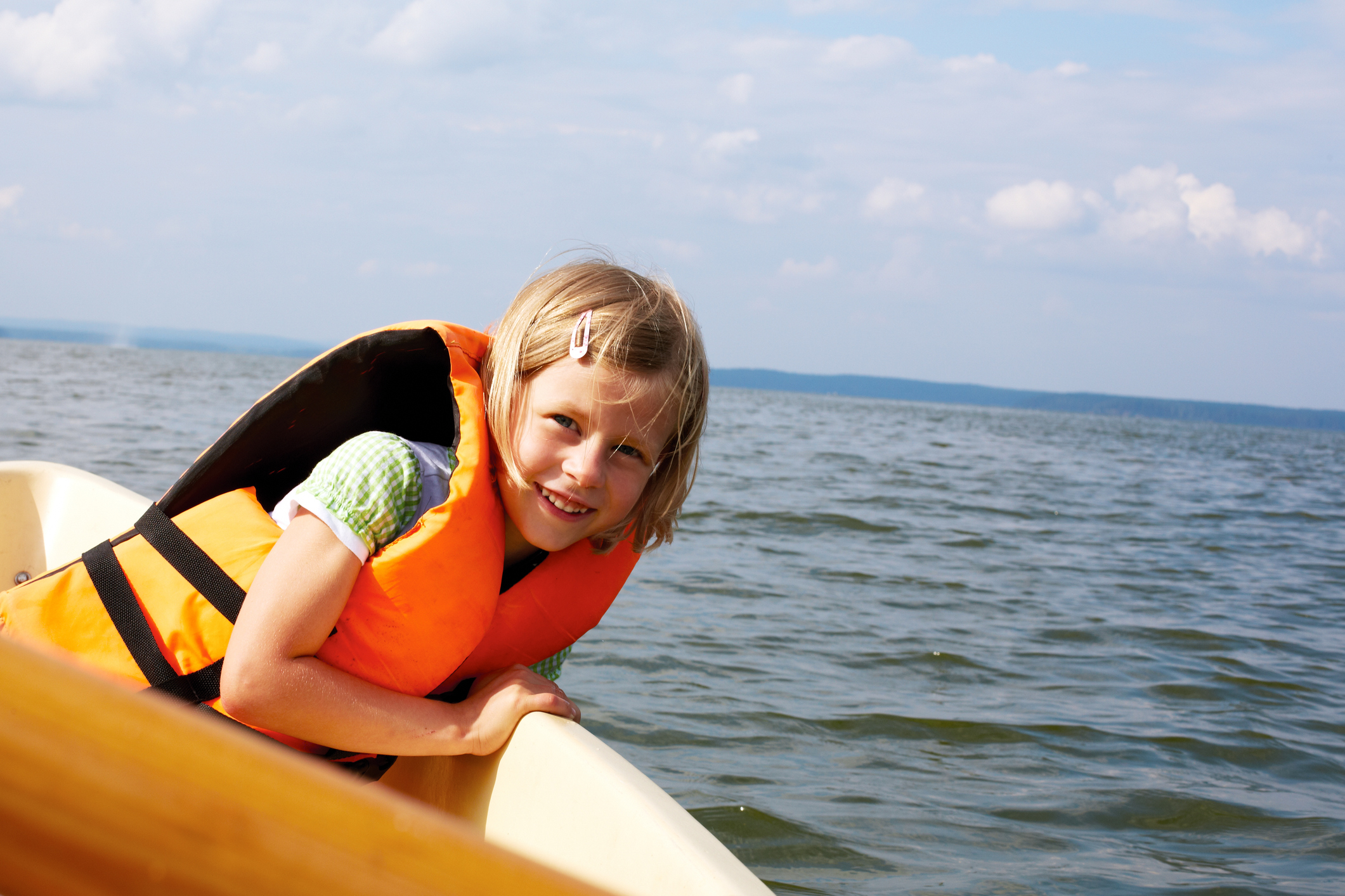 little girl dressed in life vest in a boat floats