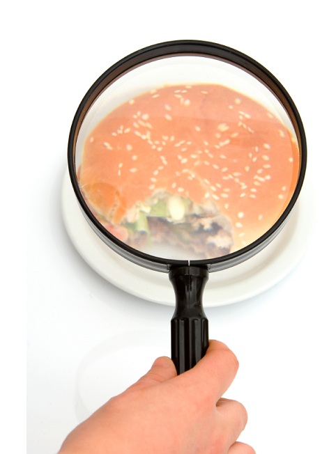 person inspecting a hamburger with a magnifying glass