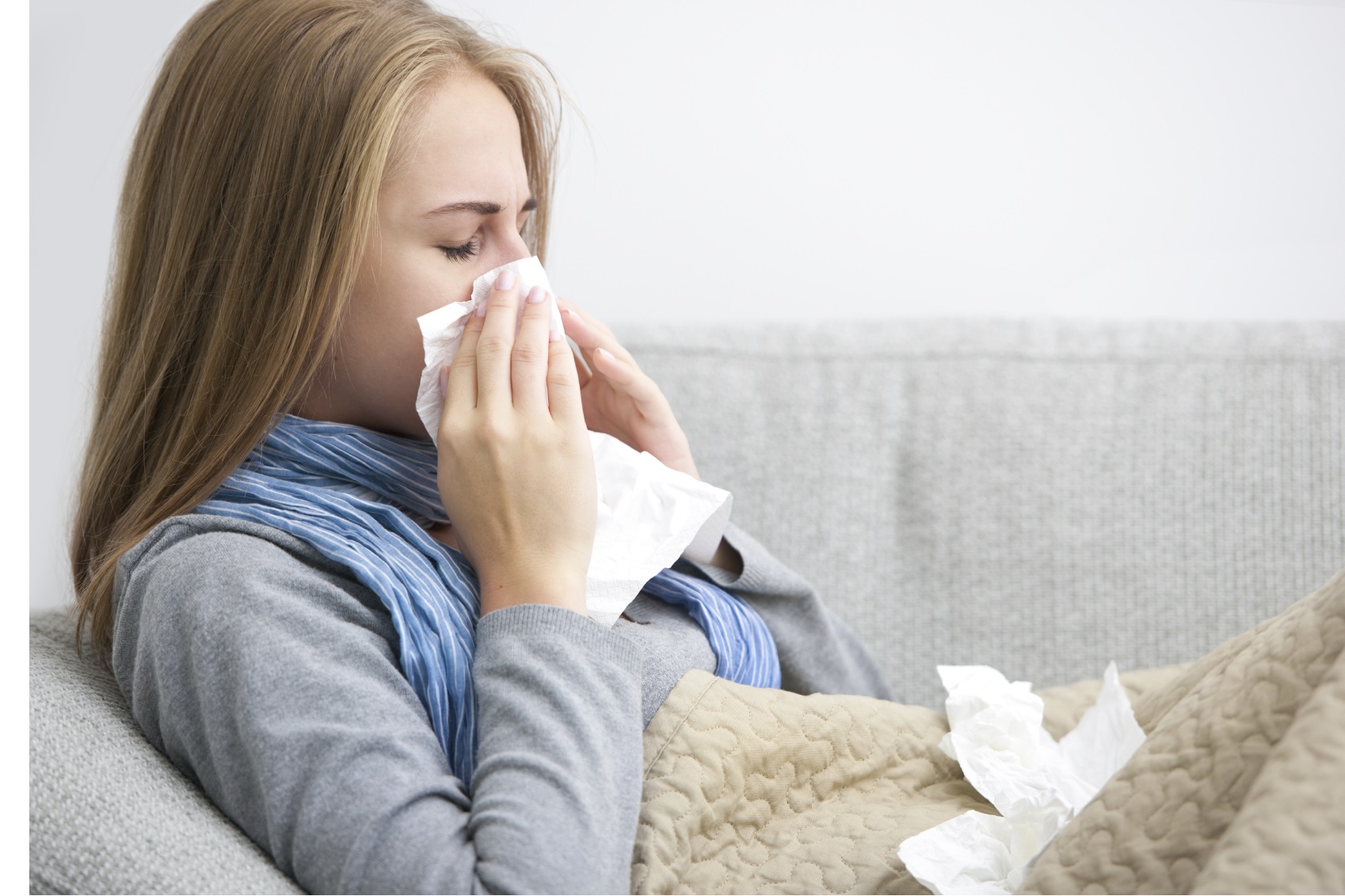 Image of woman ill with the flu, blowing her nose.