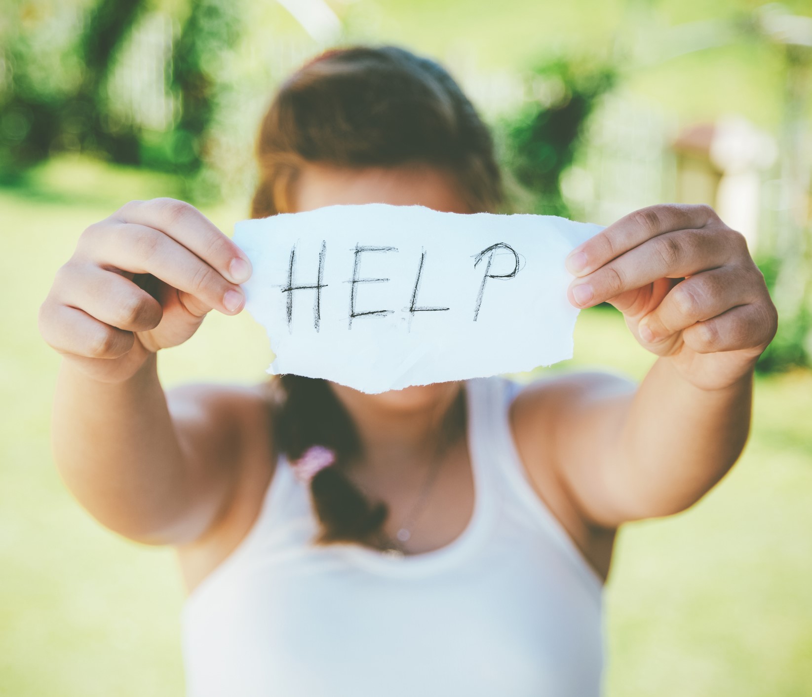 Young Desperate Girl Holding Sign that says Help.