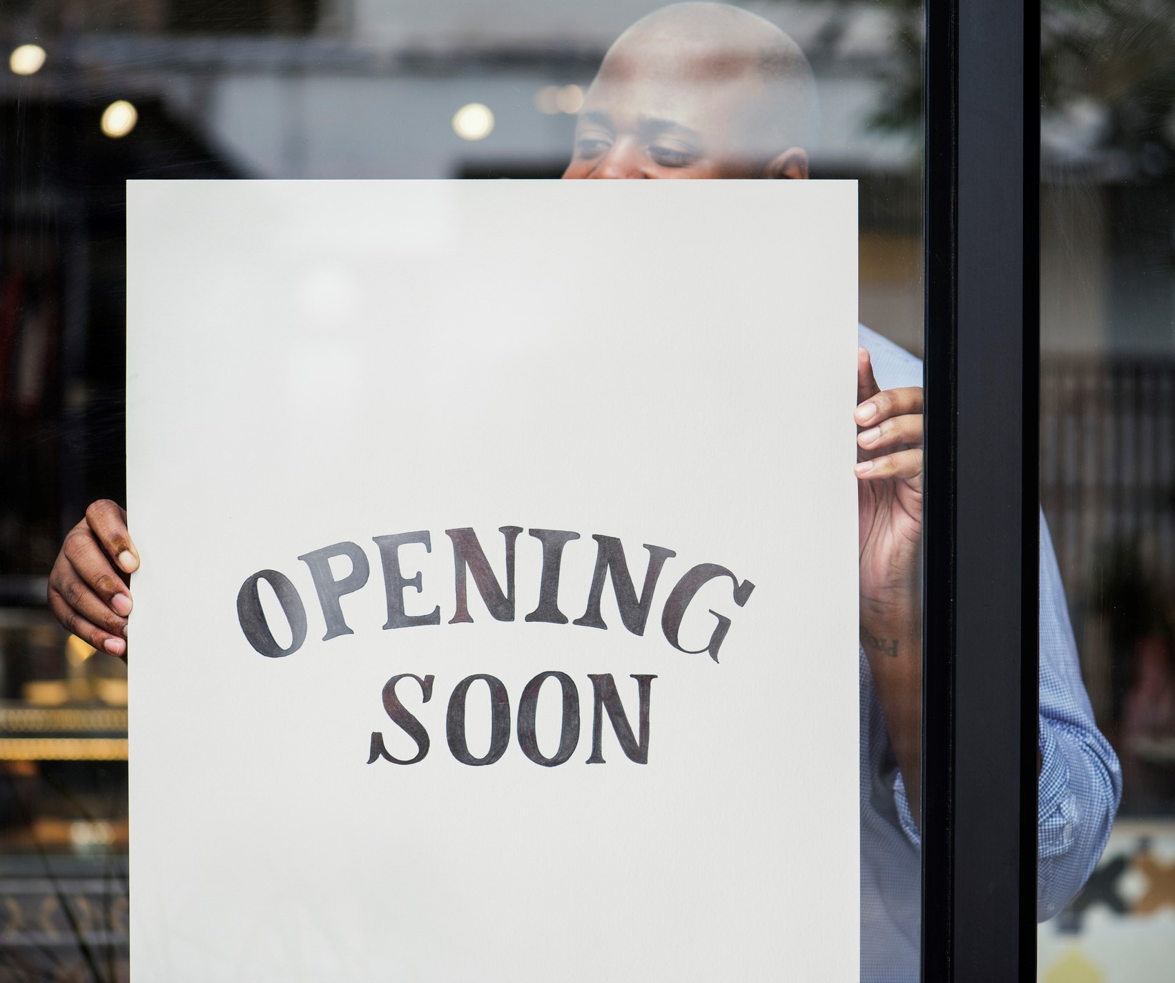 Business owner putting an Opening Soon sign in a window