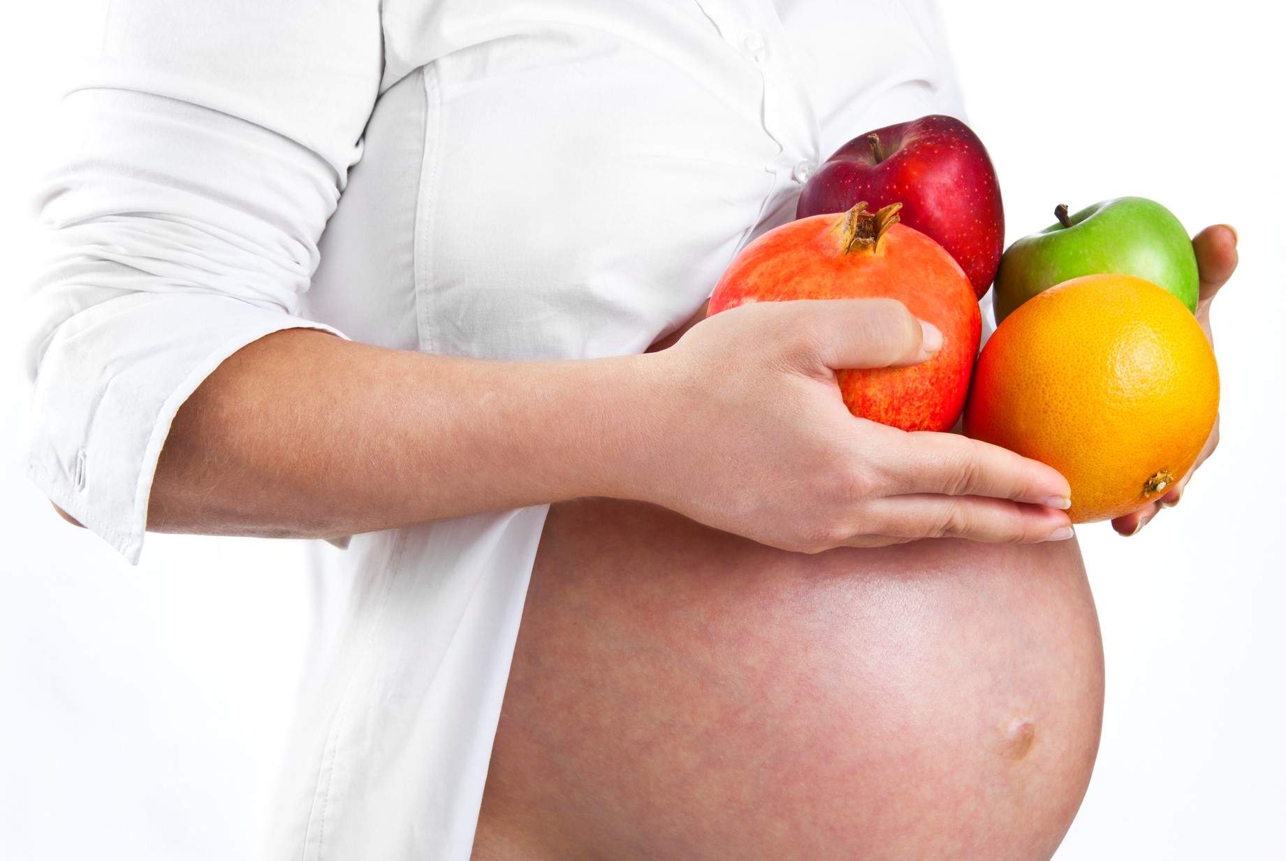 A pregnant woman holding fruit.