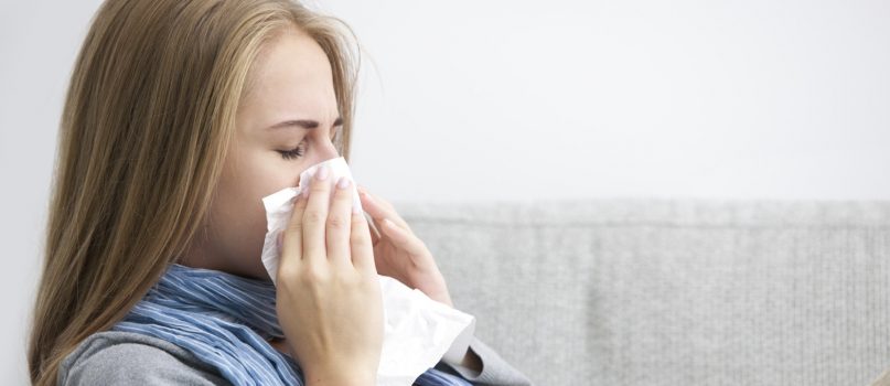 Portrait of a young woman sneezing In to tissue